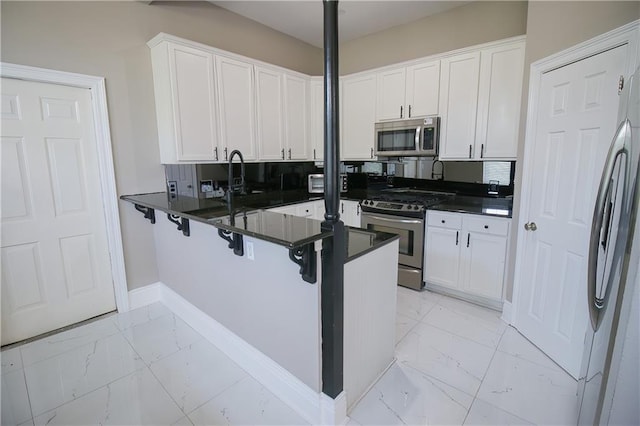 kitchen featuring kitchen peninsula, a breakfast bar, white cabinets, and stainless steel appliances