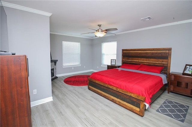 bedroom featuring a fireplace, hardwood / wood-style floors, ceiling fan, and crown molding