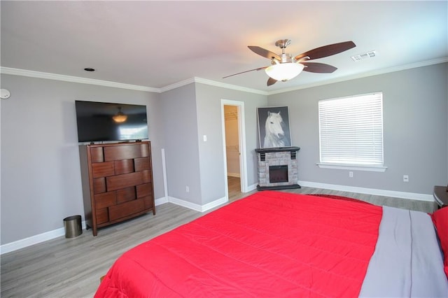 bedroom featuring hardwood / wood-style flooring, ceiling fan, a fireplace, and crown molding