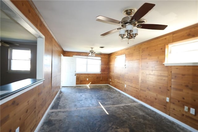 unfurnished room with ceiling fan and wood walls