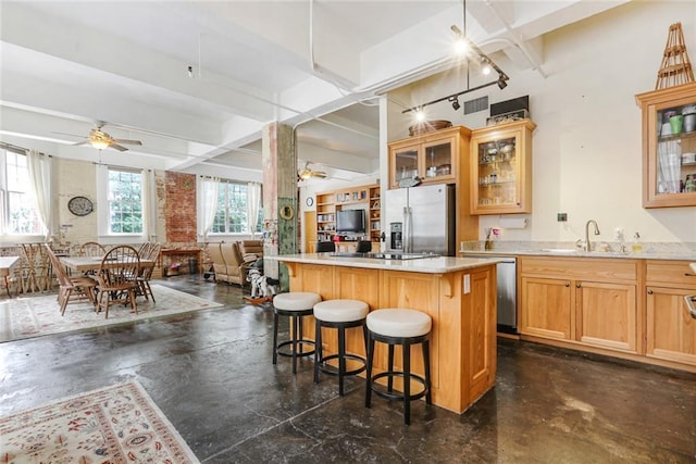 kitchen with a breakfast bar, stainless steel appliances, ceiling fan, beam ceiling, and a center island