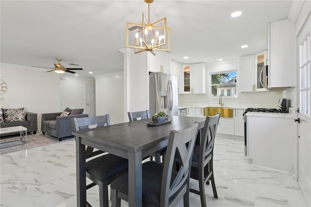 dining space featuring ceiling fan with notable chandelier and sink