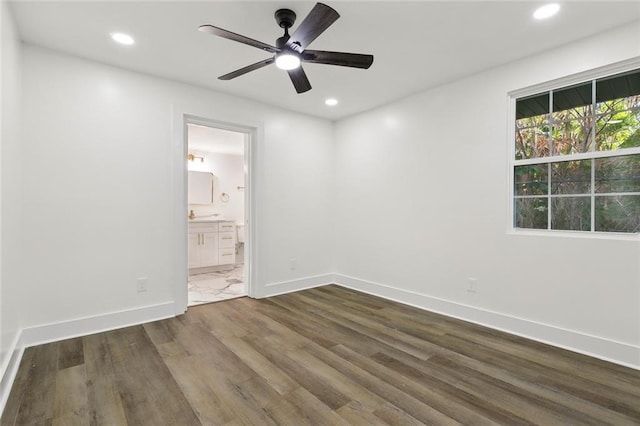 unfurnished bedroom featuring ensuite bathroom, ceiling fan, and dark wood-type flooring