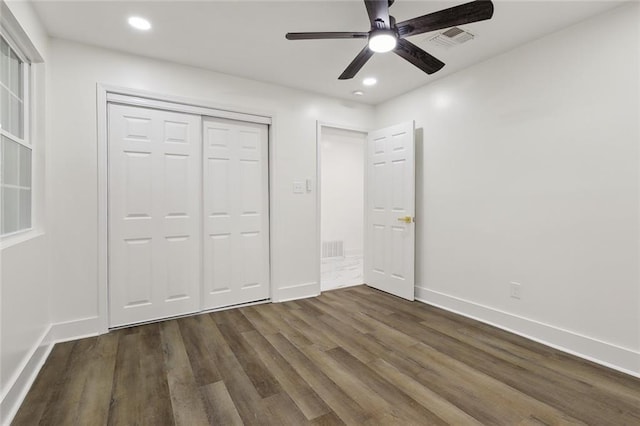 unfurnished bedroom featuring ceiling fan, a closet, and dark wood-type flooring