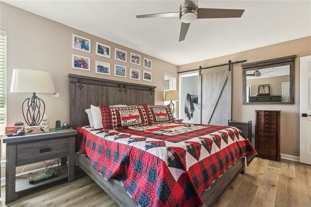 bedroom featuring ceiling fan, light hardwood / wood-style floors, and multiple windows