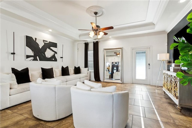 tiled living room featuring a raised ceiling, ceiling fan, and crown molding