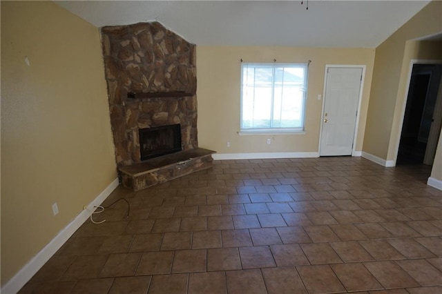 unfurnished living room featuring a fireplace, dark tile patterned flooring, and lofted ceiling