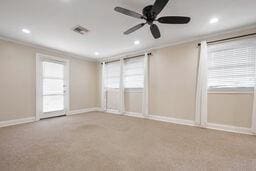 carpeted spare room featuring ceiling fan, a healthy amount of sunlight, and crown molding