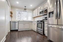 kitchen featuring stainless steel appliances, white cabinetry, dark hardwood / wood-style floors, and sink