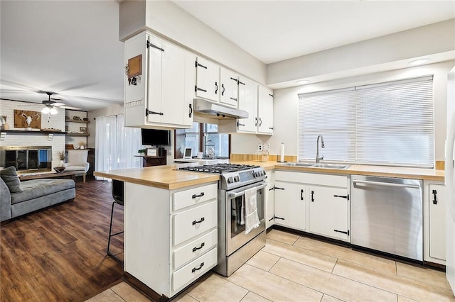 kitchen with white cabinetry, sink, a kitchen breakfast bar, kitchen peninsula, and appliances with stainless steel finishes