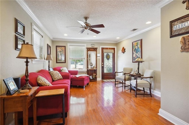 living room with crown molding, hardwood / wood-style floors, ceiling fan, and a textured ceiling