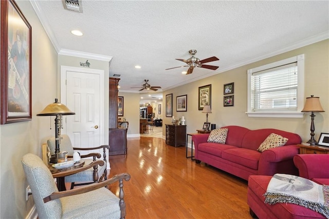 living room featuring a textured ceiling, hardwood / wood-style flooring, ceiling fan, and crown molding