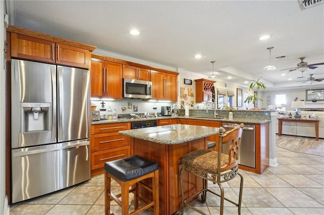 kitchen featuring a kitchen bar, appliances with stainless steel finishes, kitchen peninsula, light stone countertops, and a center island