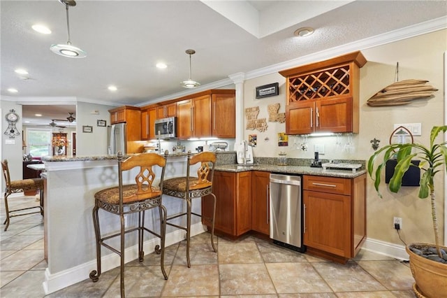 kitchen featuring light stone counters, kitchen peninsula, crown molding, decorative light fixtures, and appliances with stainless steel finishes