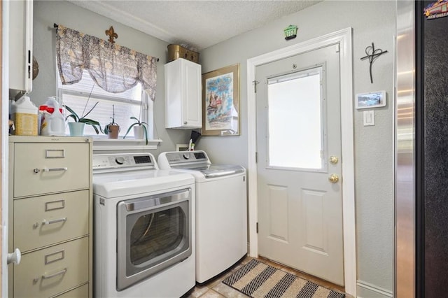 laundry room with washer and clothes dryer, cabinets, a textured ceiling, and a wealth of natural light