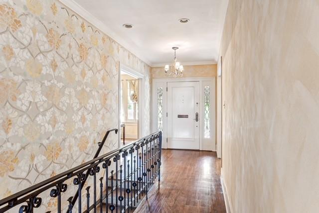 hallway featuring dark hardwood / wood-style flooring, ornamental molding, and a chandelier