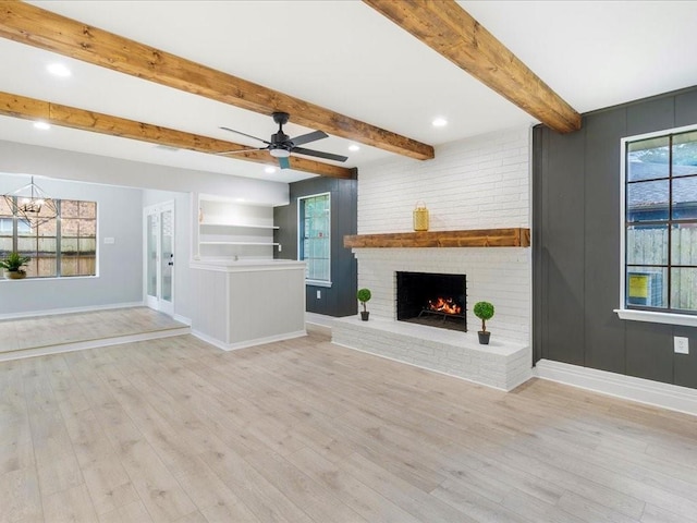 unfurnished living room with a brick fireplace, ceiling fan, light hardwood / wood-style floors, and beam ceiling