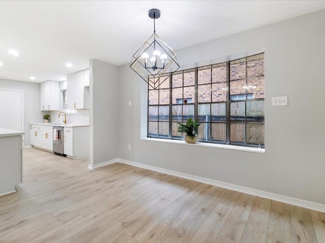 unfurnished dining area featuring light hardwood / wood-style floors, an inviting chandelier, and sink