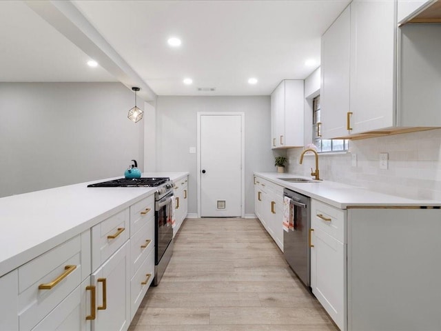 kitchen with pendant lighting, stainless steel appliances, light hardwood / wood-style floors, white cabinets, and sink