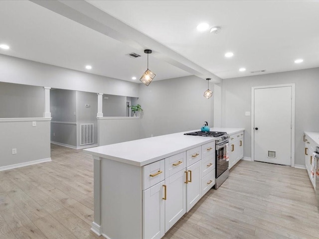 kitchen featuring decorative light fixtures, white cabinets, stainless steel gas range oven, and light hardwood / wood-style flooring