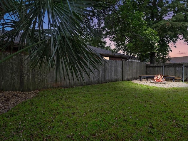 yard at dusk featuring an outdoor fire pit