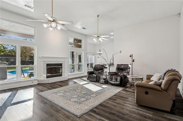 living room with a fireplace, ceiling fan, and dark wood-type flooring