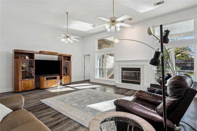 living room with a fireplace, a towering ceiling, dark hardwood / wood-style floors, and ceiling fan