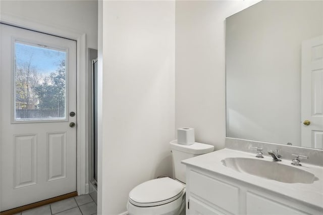 bathroom featuring tile patterned flooring, vanity, toilet, and an enclosed shower