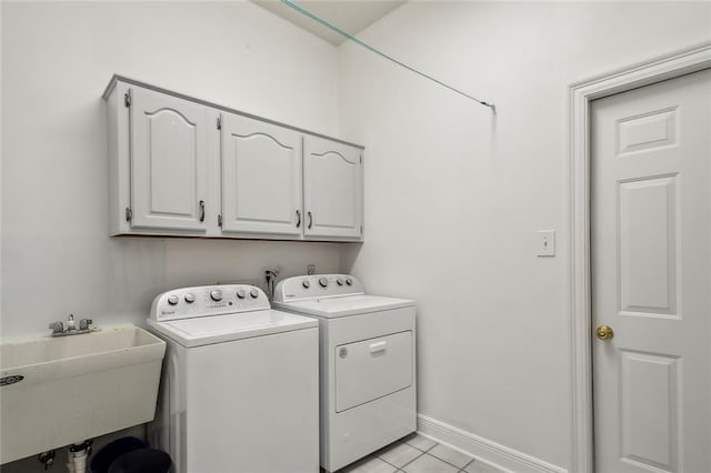 clothes washing area with washing machine and clothes dryer, sink, light tile patterned floors, and cabinets