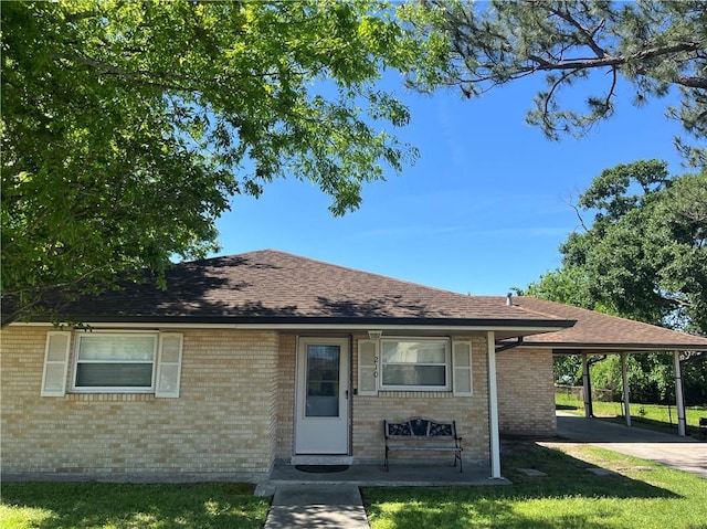 ranch-style home with a carport, brick siding, and a shingled roof