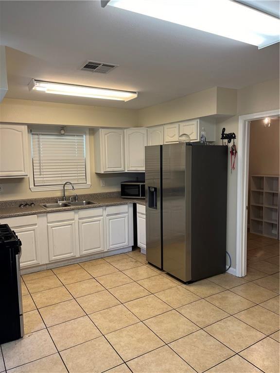 kitchen with a sink, visible vents, white cabinetry, appliances with stainless steel finishes, and dark countertops