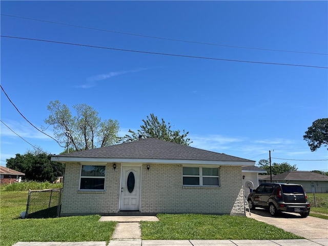 bungalow with concrete driveway, brick siding, a front yard, and fence