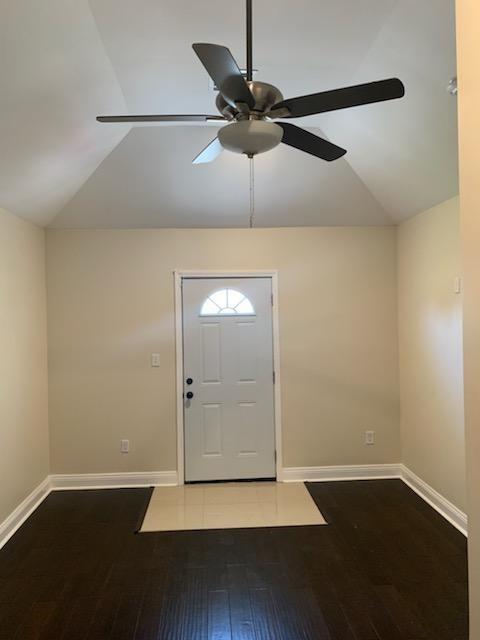 entrance foyer with lofted ceiling, ceiling fan, wood finished floors, and baseboards