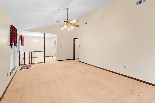 spare room featuring ceiling fan with notable chandelier, light colored carpet, and lofted ceiling