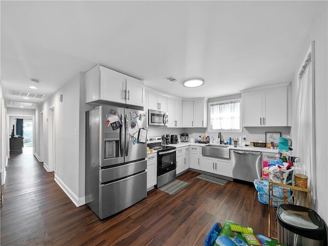 kitchen with sink, dark wood-type flooring, white cabinetry, and appliances with stainless steel finishes