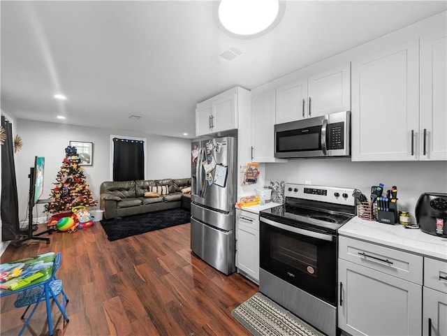 kitchen featuring white cabinets, light stone countertops, appliances with stainless steel finishes, and dark hardwood / wood-style flooring