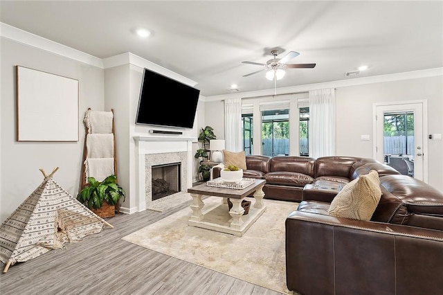 living room featuring a high end fireplace, crown molding, ceiling fan, and wood finished floors