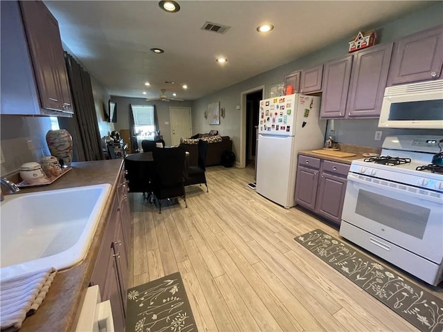 kitchen with light wood-type flooring, white appliances, ceiling fan, sink, and butcher block countertops