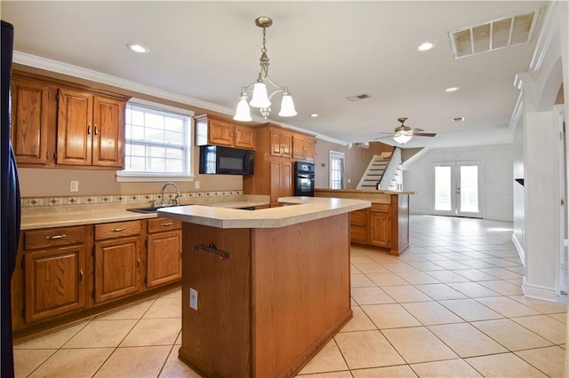 kitchen with black appliances, ceiling fan with notable chandelier, crown molding, light tile patterned floors, and a kitchen island