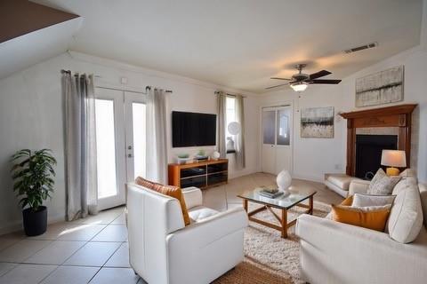 tiled living room with french doors, lofted ceiling, ceiling fan, and a healthy amount of sunlight