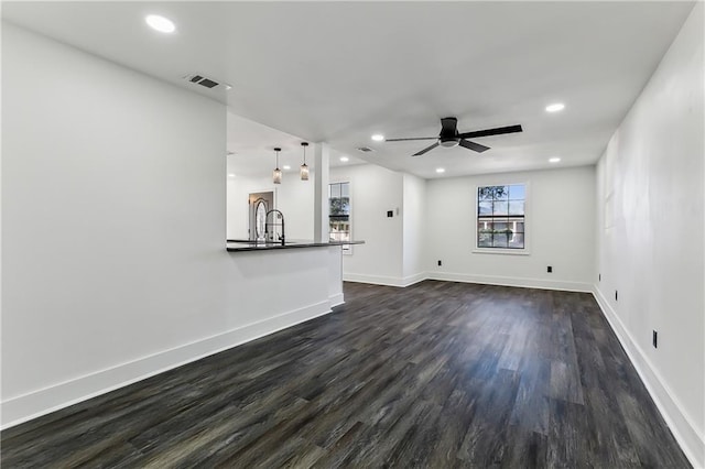 unfurnished living room featuring dark hardwood / wood-style floors, ceiling fan, and sink