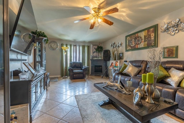 living room featuring ceiling fan, light tile patterned floors, and a fireplace