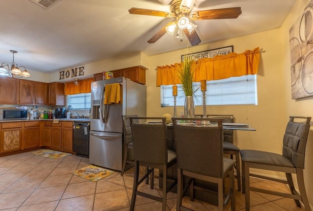 kitchen with light tile patterned floors, appliances with stainless steel finishes, ceiling fan with notable chandelier, and hanging light fixtures