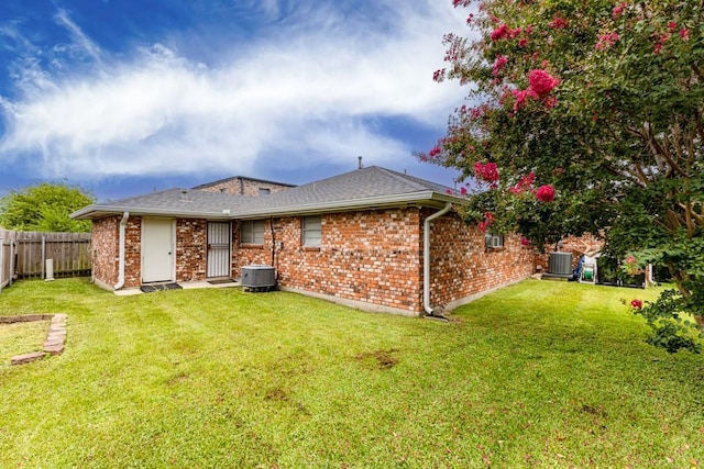 back of house with central AC unit and a lawn