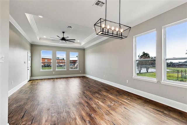 spare room with crown molding, dark hardwood / wood-style floors, ceiling fan with notable chandelier, and a tray ceiling