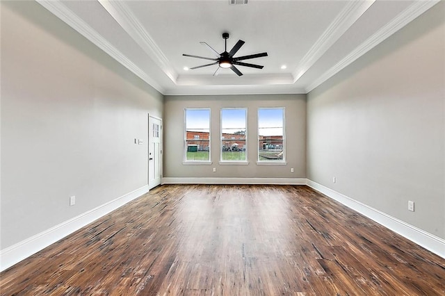 empty room with a raised ceiling, ornamental molding, dark wood-type flooring, and ceiling fan