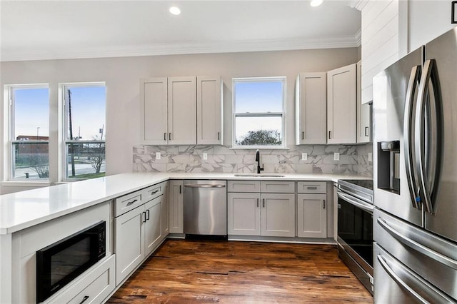 kitchen featuring tasteful backsplash, ornamental molding, appliances with stainless steel finishes, and sink