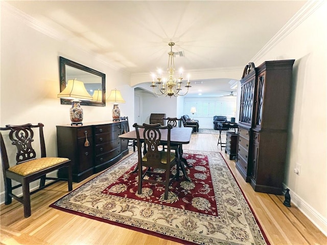 dining room with crown molding, light hardwood / wood-style flooring, and a chandelier