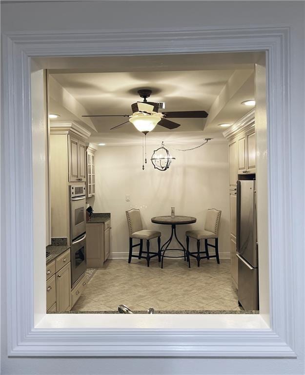 kitchen featuring ceiling fan, a kitchen bar, appliances with stainless steel finishes, and cream cabinets