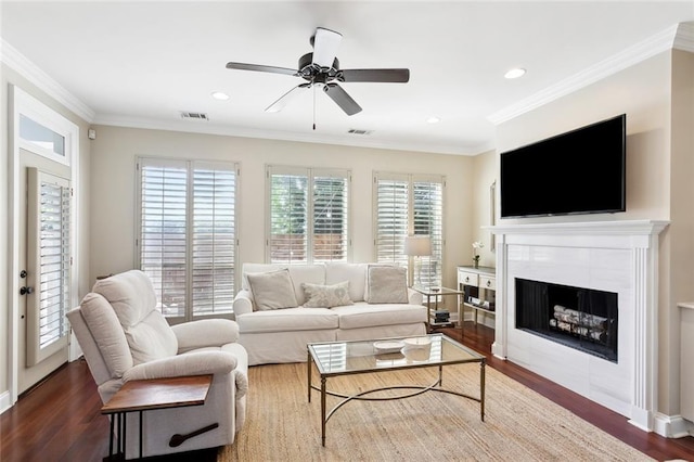 living room with a tile fireplace, dark hardwood / wood-style flooring, plenty of natural light, and ceiling fan